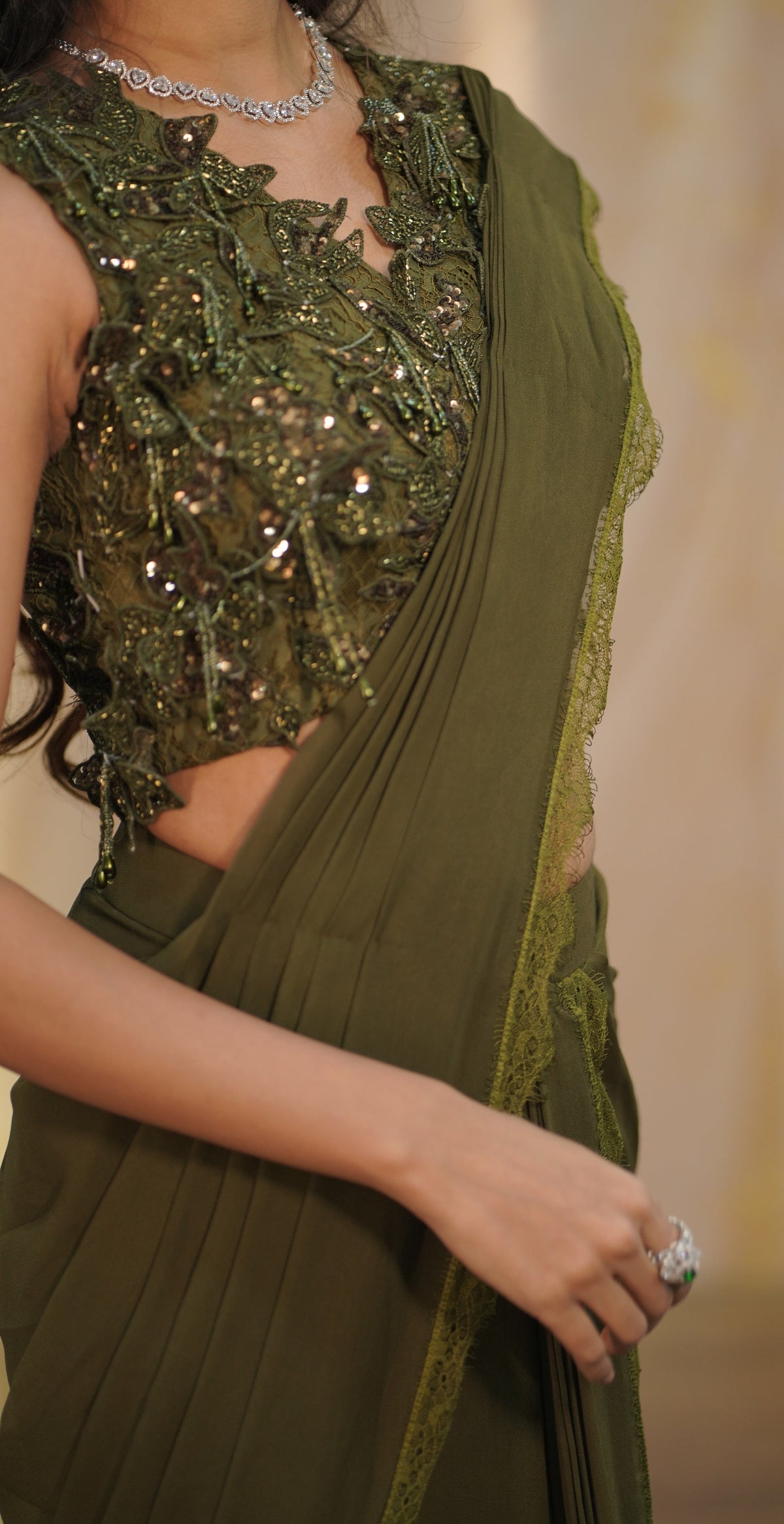 An olive green sari with a heavily embellished, sequined floral blouse